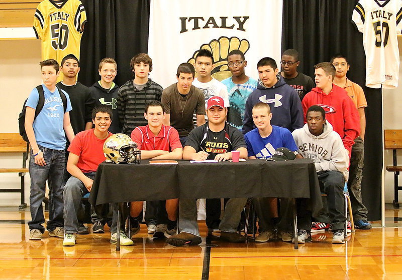 Image: Senior Gladiator Zain Byers surrounds himself with several Italy Junior High student-athletes as he signs his letter of commitment to play football for Austin College. Zain’s message to the younger players was for each of them to commit to becoming a better student and someday they could be signing their own commitment letter to compete at the college level.