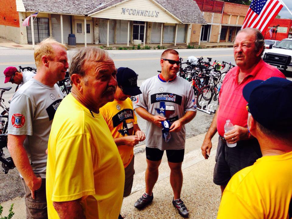 Image: Mayor James Hobbs and Ronnie Hyles,  retired Dallas firefighter, talk with the visiting riders and support staff.