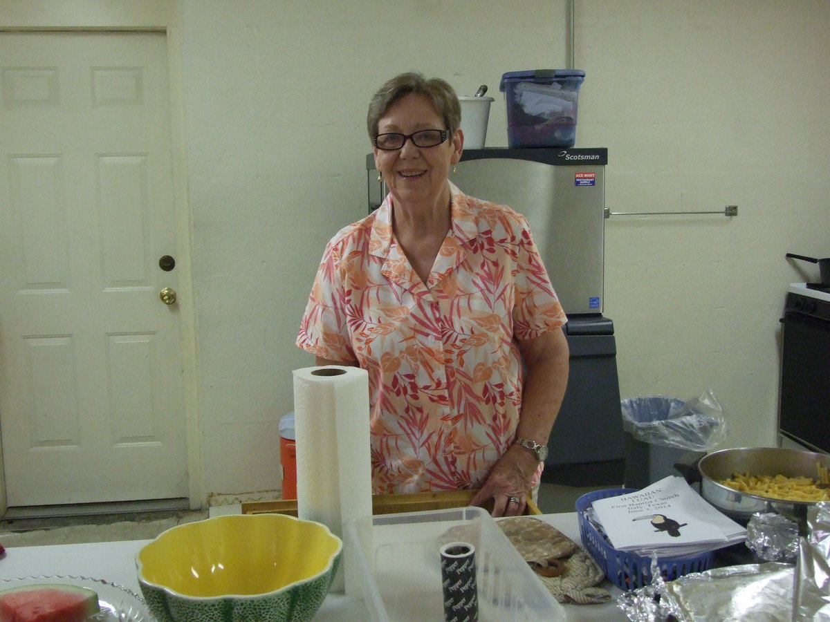 Image: Linda Goodman helps prepare the food for the luau.