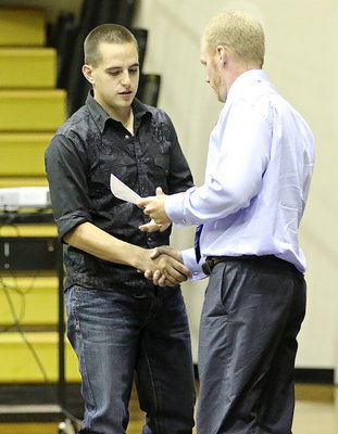 Image: Cody Medrano shakes hands with Coach Jon Cady as he accepts his sports participation certificate.