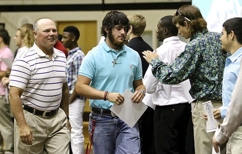 Image: Kyle Fortenberry accepts his sports participation certificate from Coach Jackie Cate and then accepts congratulations from teammate Ty Windham.