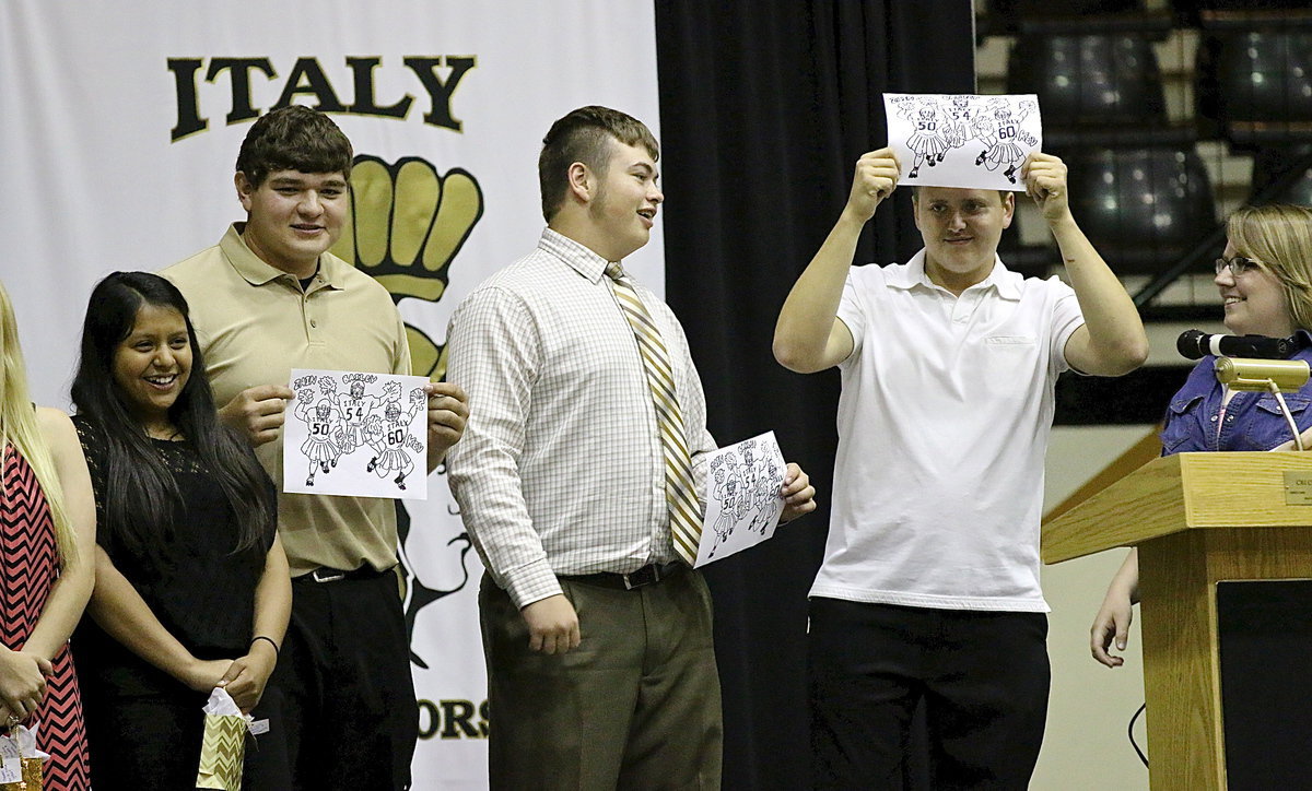 Image: Miss Catherine Hewett presents honorary cheerleaders Kevin Roldan, Zain Byers and Bailey Walton with revived sketches of them wearing tutus and shoulder pads while waving pom-poms after their death-defying stunt performed during the Homecoming pep rally. Britney Chambers was not harmed while attempting the stunt.