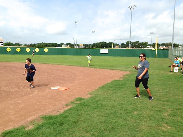 Image: Softball Coach Tina Richards encourages her hitters as they make their way down the first base line.