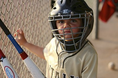 Image: Tripp Slovak(12) gets ready in the dugout before taking the field as catcher for the IYAA T-Ball Gladiators.
