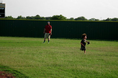 Image: Dash Reid helps his dad, Travis, in the outfield.