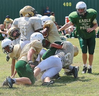 Image: JV Gladiator Austin Crawford(62) pulls down an Eagle runner with help from teammate Kendrick Norwood(4).