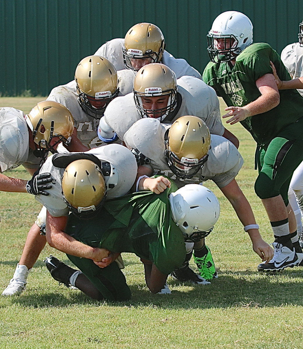 Image: Gladiator defenders Kyle Fortenberry(50) and John Escamilla(21) are joined by teammates in stopping the progress of an Eagle runner.