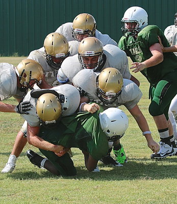 Image: Gladiator defenders Kyle Fortenberry(50) and John Escamilla(21) are joined by teammates in stopping the progress of an Eagle runner.
