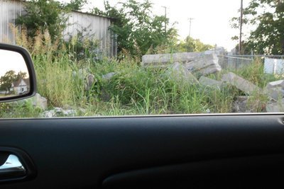 Image: This concrete and weeds are adjacent to the city barn area. Not sure who owns this area but it is a safety hazard so the city should either take care of the mess or force the owner to do so.