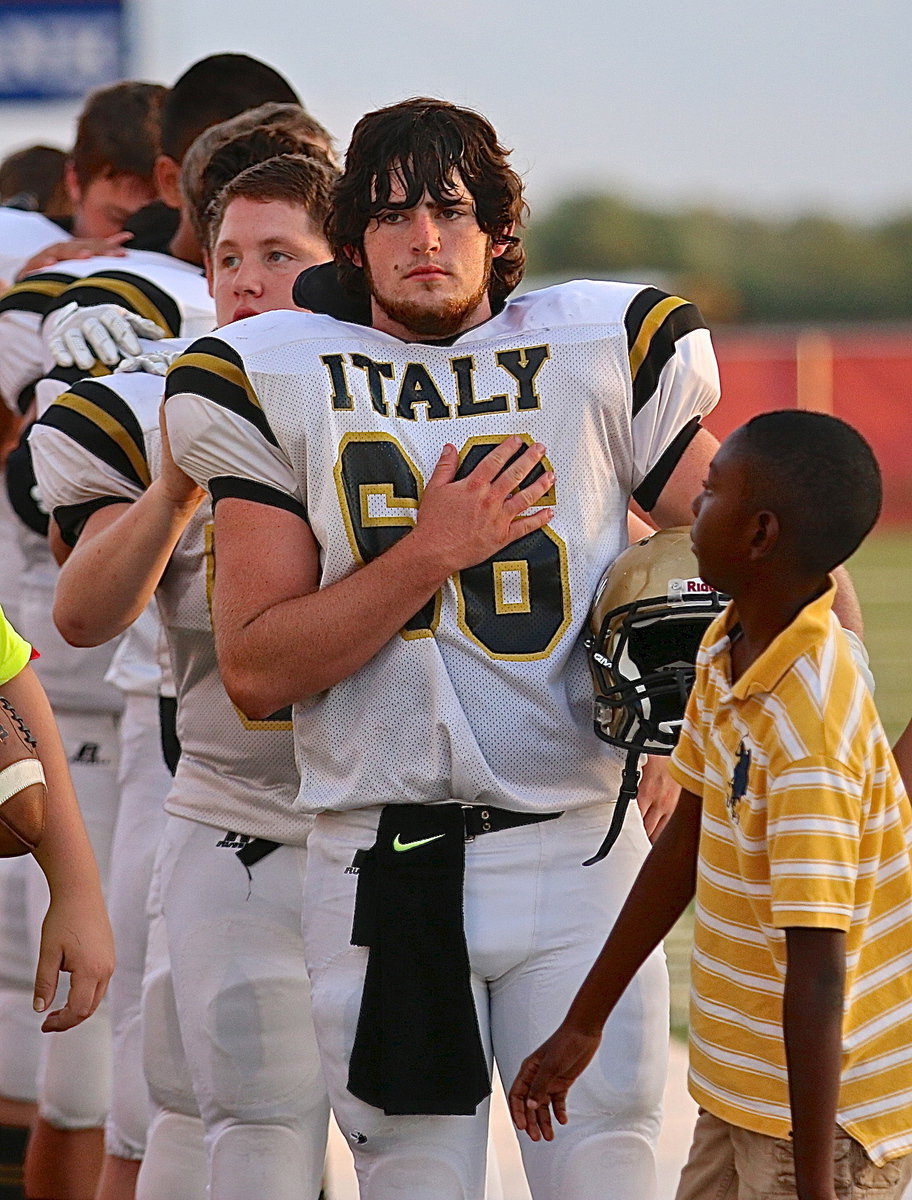 Image: Kyle Fortenberry(66) and John Escamilla(50) show respect to the flag before soldiering the field.