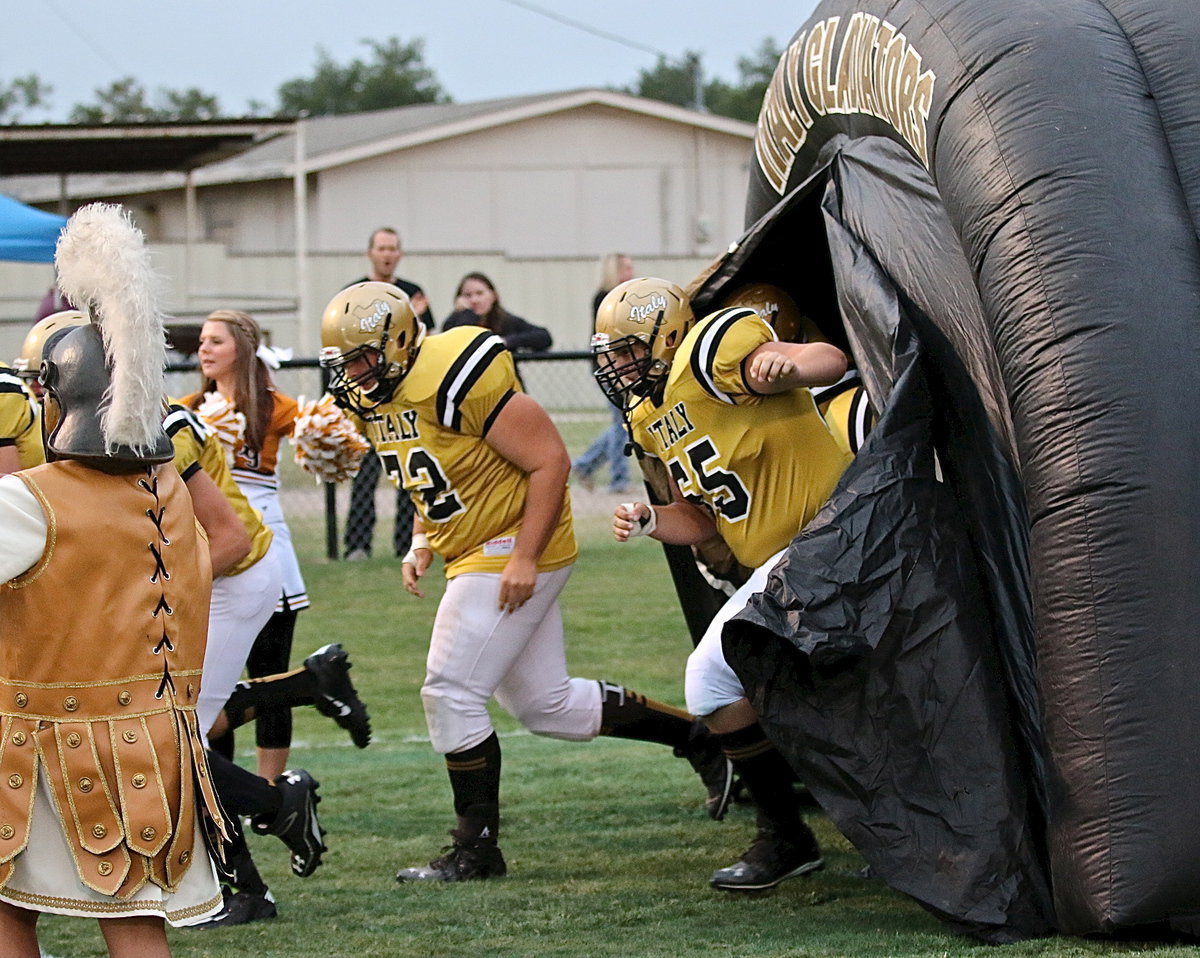 Image: Italy’s Aaron Pittmon(72) and Austin Pittmon(65) bust out of the tunnel to help lead their Gladiator teammates onto Willis Field and into battle against Blooming Grove.