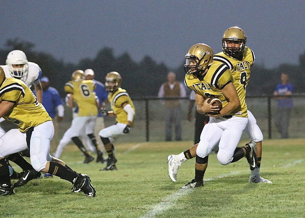 Image: Gladiator quarterback Joe Celis(8) hands off to senior tailback Hunter Merimon(3).