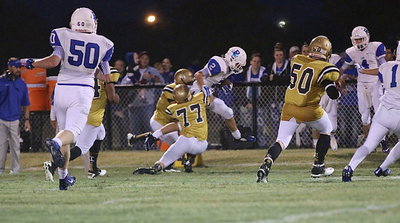 Image: Clay Riddle(77) helps a teammate drag down a Blooming Grove kick returner.