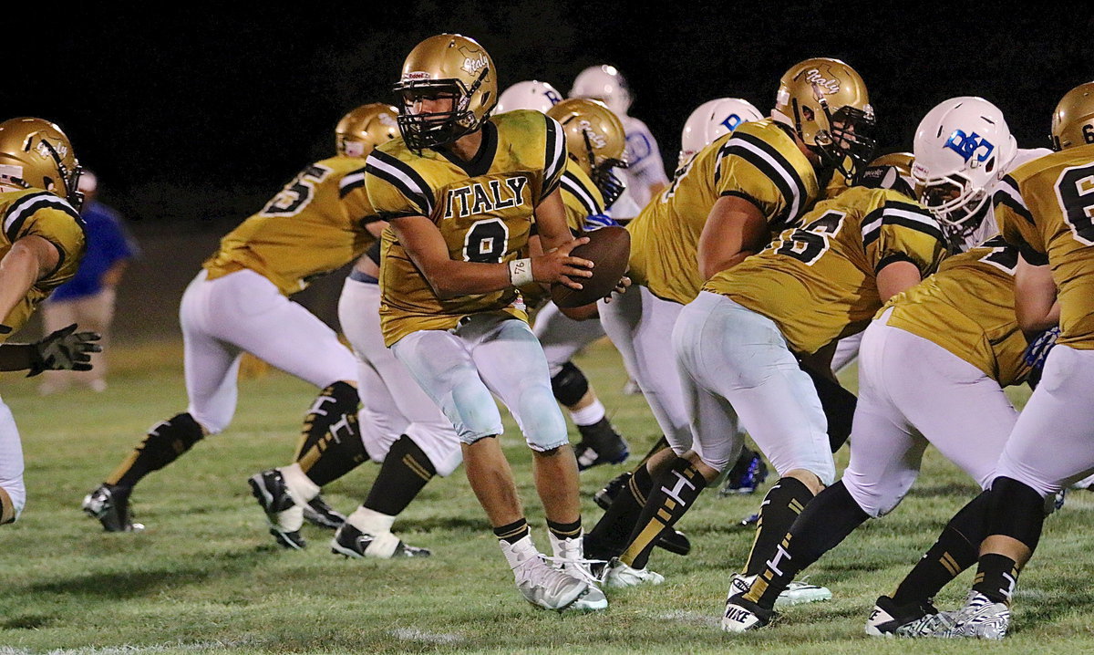 Image: Quarterback Joe Celis(9) takes the snap from senior center Kyle Fortenberry(66).