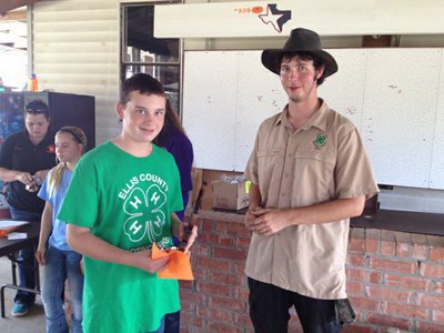 Image: Hunter Hinz, left, accepts his trophy at the Ellis County tournament. Right, is Matt Dawson, 2014 Maypearl High School graduate and graduate of the Ellis County Shooting Sports 4-H Club. Dawson won the adult division and remains with the club as a coach.