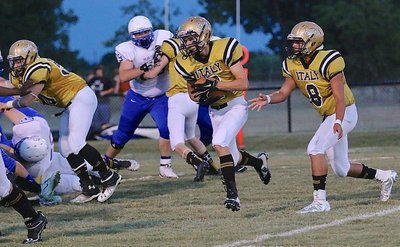 Image: Gladiator quarterback Joe Celis(8) hands off to receiver Ryan Connor(7) as guard John Escamilla(50) and the rest of the Italy offensive line try to create a running lane.