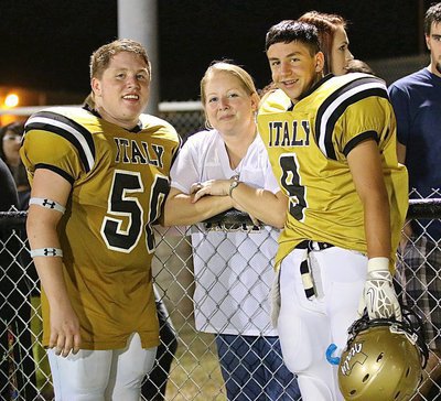 Image: Proud mom, Misty Escamilla poses with her two sons, John “J.T.” Escamilla(50), a senior, and Gary Escamilla(9), a freshman. Both brothers entered the game against Frost for the Gladiators.