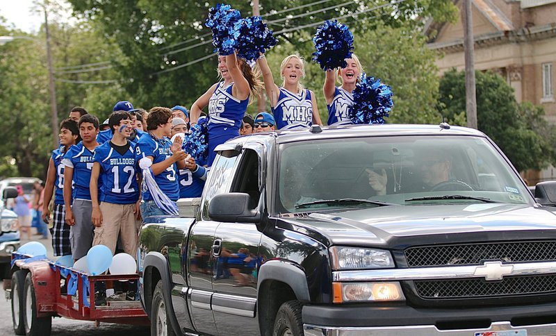 Image: Here come the Milford Bulldogs with their cheerleaders Gabby Rose, Corrie Dawkins and Evy Ewing leading the yells during the school’s 2014 Homecoming Parade as it convoys thru downtown Milford.