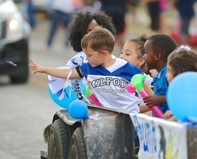 Image: Porter Montgomery(14), currently a flag football player for Milford, passes a candy treat to his family during the homecoming parade.