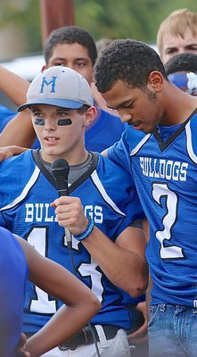 Image: Pre-game motivational speech form Keith Kayser(13) fires up the town of Milford with teammate TraVion Jones(2) being supportive.