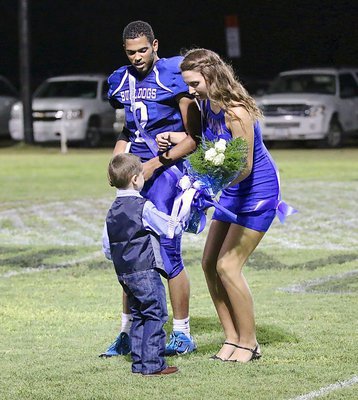 Image: King nominee TraVion Jones is impressed by the maturity of Mr. Landon Potter as he presents Gabby Rose with a bouquet of flowers.