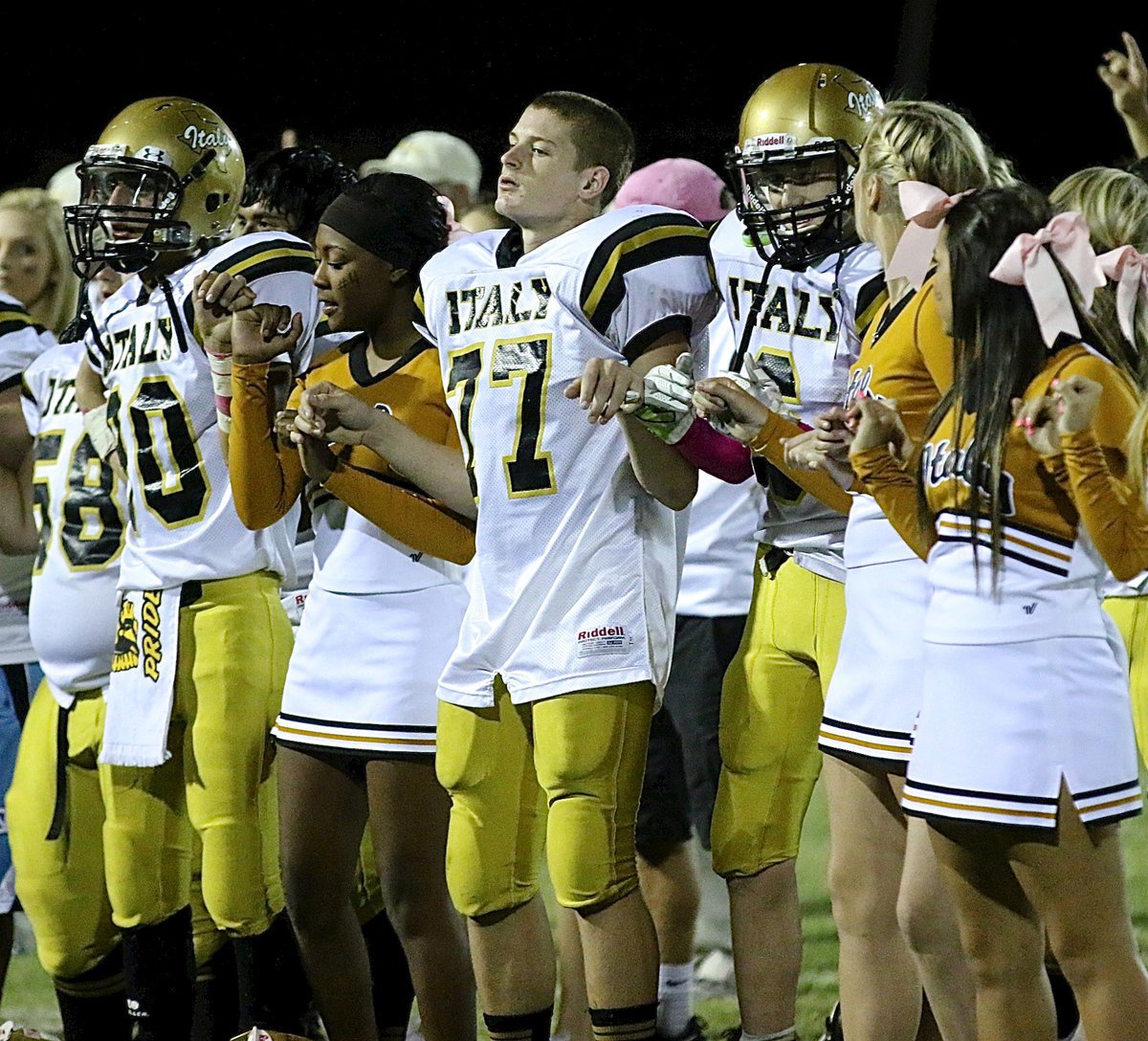 Image: Jack Hernandez(80), K’Breona Davis, Clay Riddle(77), Clayton Miller(6), Madison Washington and Ashlyn Jacinto stick together during the school song.