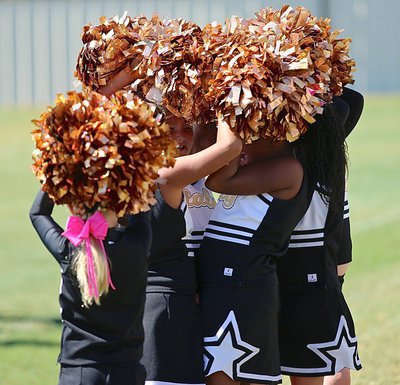 Image: The IYAA B-team cheerleaders huddle up under an umbrella of pom-poms.