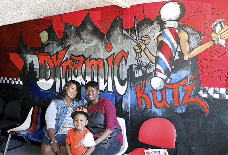 Image: Dynamic Kut’z owner Cynthia Singleton Chance, her nephew Adrian “Deuce” Griffin and Beautician Na’Koia Hailey, aka KoKoFiveO, pose in front of the wall mural painted by Cynthia herself. It was Customer Appreciation Day at Dynamic Kut’z with music, food and haircuts for all.