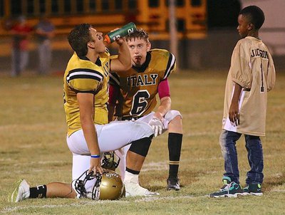 Image: Gladiator brothers Hunter Merimon(3) and Clayton Miller(6) take a knee while being rehydrated by waterboy Darrin Jackson(1).