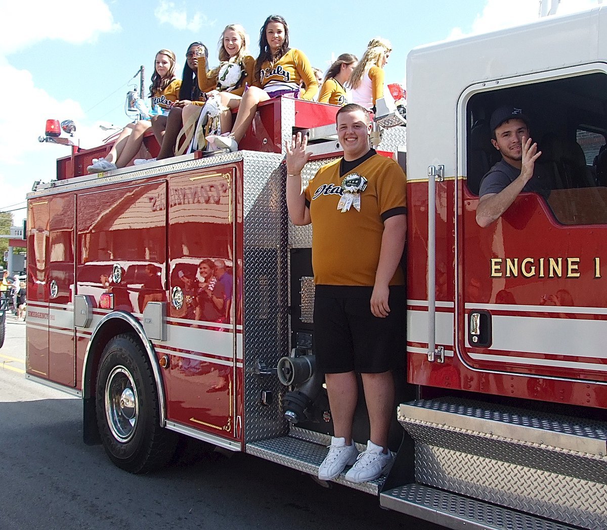 Image: Italy firefighter Brandon Jacinto and cheerleaders Zac Mercer, Brooke DeBorde, K’Breona Davis, Britney Chambers and Ashlyn Jacinto wave and throw candy to the crowd.