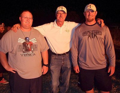 Image: Coaches Brandon Ganske, Charles Tindol and Jon Proud bask in the glow of the homecoming bonfire.