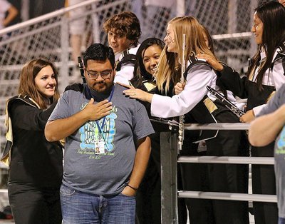 Image: Band members shoulder pat band director Jesus Perez during the pre-game anthem.