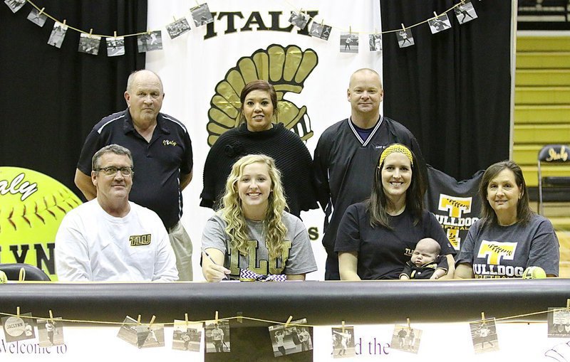 Image: Italy’s Lady Gladiator Softball coaches have gone from behind the scenes to the back row during a commitment ceremony held in honor of star pitcher Jaclynn Lewis. Back row (L-R): Coach Johnny Jones, Head softball coach Tina Richards, Coach Michael Chambers. Front row (L-R): Russ Lewis, Jaclynn Lewis, Megann Lewis Harlow, Renn Harlow and Kelly Lewis.