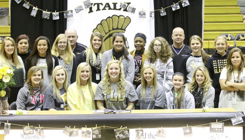 Image: Members of the 2015 Lady Gladiator Softball team surround teammate Jaclynn Lewis on her special day as Lewis commits to Texas Lutheran University. Back row (L-R): Hannah Washington, Head Coach Tina Richards, April Lusk, Paige Cunningham, Coach Johnny Jones, Sydney Weeks, Jenna Holden, K’Breona Davis, Rori Russell, Coach Michael Chambers, Brooke DeBorde and Brycelyn Richards. Front row (L-R): Lillie Perry, Kelsey Nelson, Madison Washington, Jaclynn Lewis, Bailey Eubank, Tara Wallis, Britney Chambers and Jill Varner.