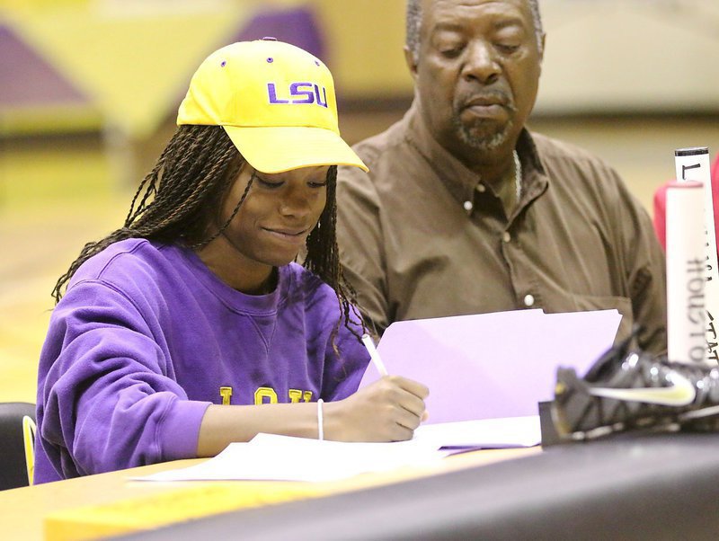 Image: Now decked out in purple and yellow, Italy High School’s Kortnei Johnson signs her letter of intent to run track for the LSU Tigers as her uncle, Danny Jennings, looks on.