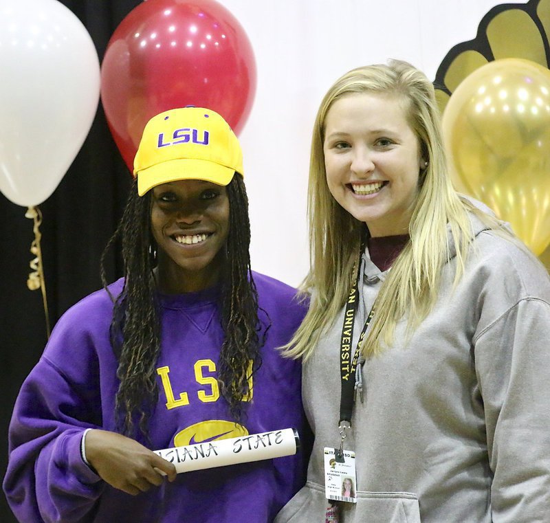 Image: Kortnei Johnson is congratulated by senior classmate Jaclynn Lewis after Johnson signed with LSU to continue her track career at the next level. Lewis committed to Texas Lutheran University in the same week to play collegiate softball.
