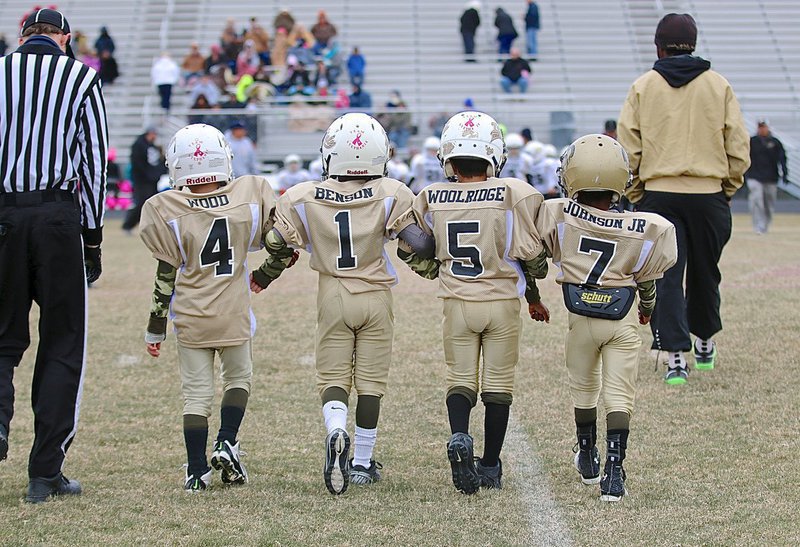 Image: Arm in arm, IYAA C-Team Gladiator 2nd grade captains Gared Wood(4), Curtis Benson(1), Damian Wooldridge(5) and Cory “Lucky” Johnson, Jr.(7) head out to midfield to greet the Palmer Bulldog captains.