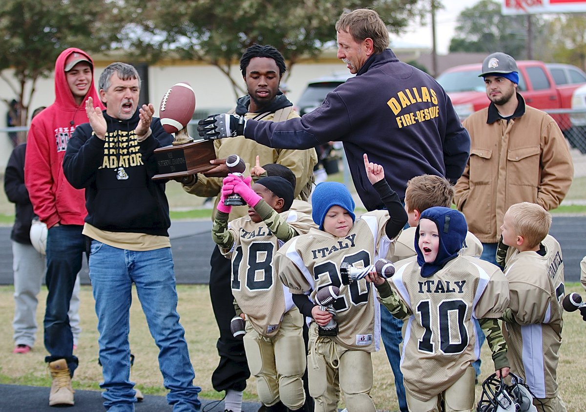 Image: IYAA President Charles Hyles presents the 2014 NEH Superbowl Trophy to C-Team Gladiator head coach Jasenio Anderson as the team receives a thunderous ovation for their efforts.