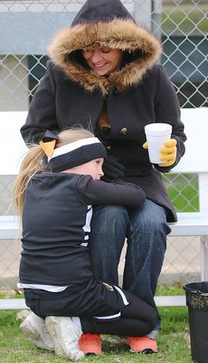 Image: Lily Hugghins uses her cheer coach, and mom, Kia Hugghins as a windbreaker in hopes of staying warm on a such a brisk morning.