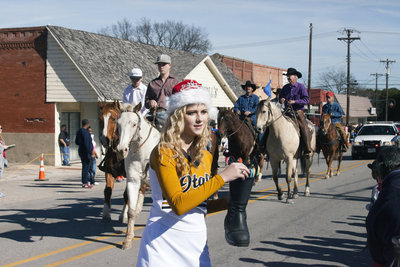 Image: Italy High School cheerleader Halee Turner passes out candy using a santa boot as cowboys and horses wrap up the parade.