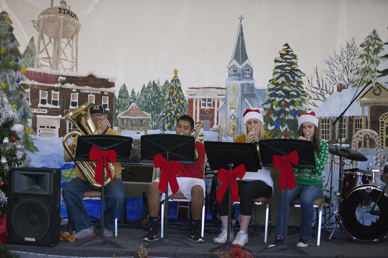 Image: Assistant band director of Italy High School David Graves and Gladiator Regiment Band members Chris Davilla, Madison Washington and Amber Hooker play Christmas music under the downtown pavilion. Notice the amazing holiday painting in the background. Created by the IHS art students and teacher Jeremiah Glover, the painting truly captures the spirit of Christmas in our little town.