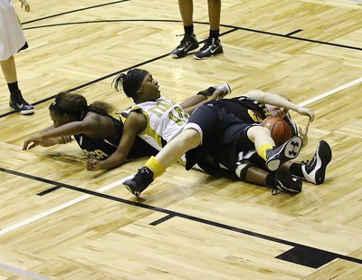 Image: K’Breona Davis(10) does the dirty work for the Lady Gladiators as she scrums for a loose ball with two Lady Wampus Cats.
