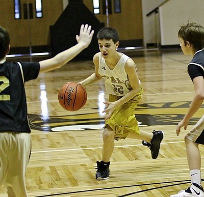 Image: 7th Grader Colby Hampton(12) dribbles into the lane to test the Jags’ defense.