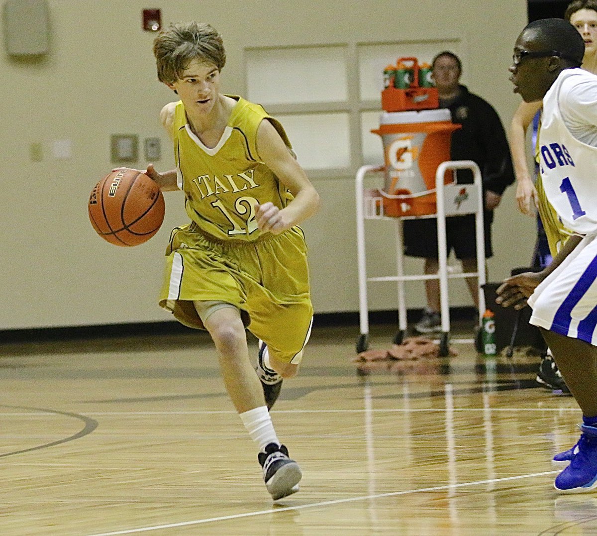 Image: JV Gladiator Garrett Janek(12) handles the ball as he makes his way across midcourt.