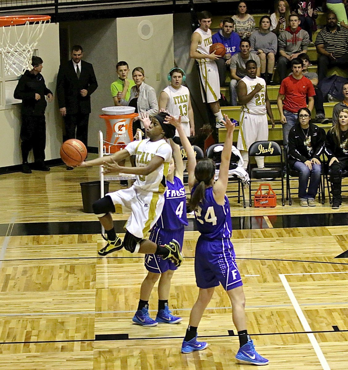 Image: Italy’s Kortnei Johnson(3) splits a wall set by two Lady Polar Bear defenders and then banks in the underhanded scoop shot.