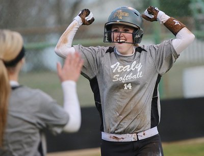 Image: Kelsey Nelson celebrates her scoring effort with her Lady Gladiator teammates waiting in the dugout.