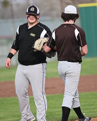 Image: John Byers gives fellow senior Kyle Fortenberry a glove tap as Fortenberry takes the mound.