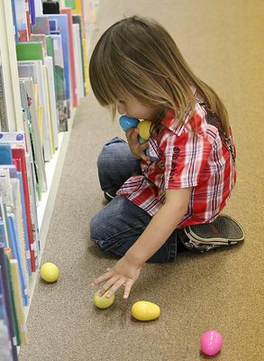 Image: Mason gathers up all the Easter eggs he can carry while hunting inside the library.