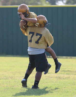 Image: Kenneth Norwood, Jr.(77) gives a teammate a lift during a form tackling drill.