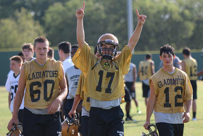Image: Clay Riddle(60), Ryan Connor(17) and Elliott Worsham(12) remain pumped up after the first half of morning practices on Tuesday.